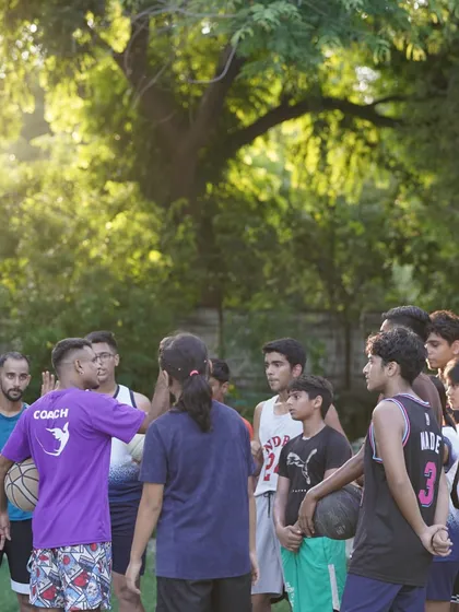 A coach speaks to the group in a beautiful outdoor setting, surrounded by trees.