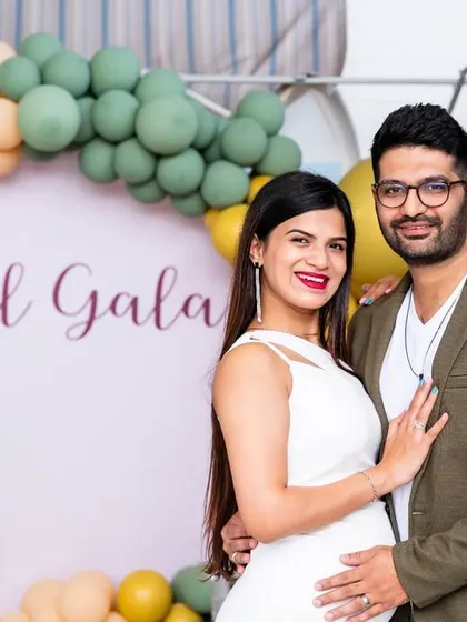 A beautiful portrait of the expecting couple posing in front of their "Lil Gala" baby shower backdrop.