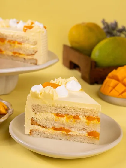 A slice of the layered mango cream cake, revealing the fresh mango pieces inside. This shot is essential to show customers the delicious interior of the cake.