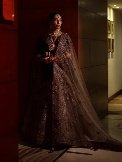 A dramatic, full-length portrait of a bride. The makeup is designed to look flawless from a distance, with well-defined features that stand out even in low light.