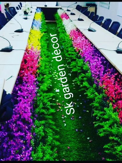 This is one of my unique corporate event decorations. I designed a long floral and greenery runner to fit inside the cutout of a large conference table. It adds a vibrant pop of color and nature to a formal meeting setting, making it more engaging.