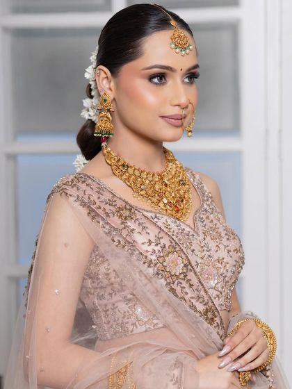 This bride looks like royalty. The sleek bun adorned with flowers, combined with the soft smokey eye, creates a sophisticated and timeless bridal look.