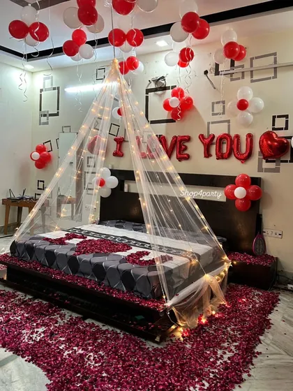 For a truly romantic gesture, we transformed this bedroom with a fairy light canopy, hundreds of red and white balloons, and a floor covered in rose petals. The "I LOVE YOU" balloon letters add a perfect finishing touch to this anniversary or birthday surprise.