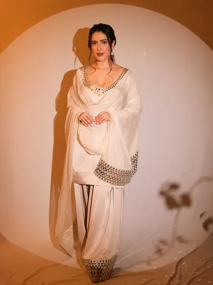 A full-length view of this elegant white Patiala suit. The makeup features a pop of red on the lips to add a touch of color and contrast to the monochrome outfit.