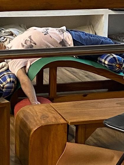 A student relaxing in a supported backbend on a curved bench. This prop is specifically designed to open the chest and support the natural curve of the spine.