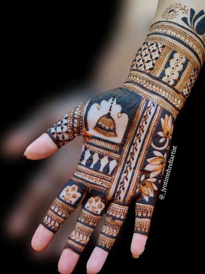 A designer henna piece with a temple bell (ghanti) motif. The bold, dark fills and geometric patterns give this design a very architectural and modern feel.