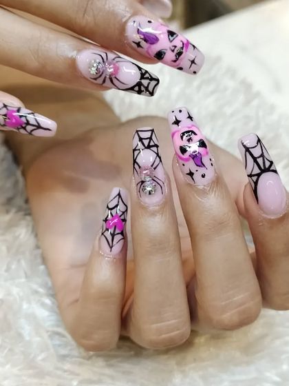 Get into the spooky spirit with our Halloween-themed nail art. This intricate design features spiderwebs, ghosts, and rhinestone spiders on long, coffin-shaped extensions.