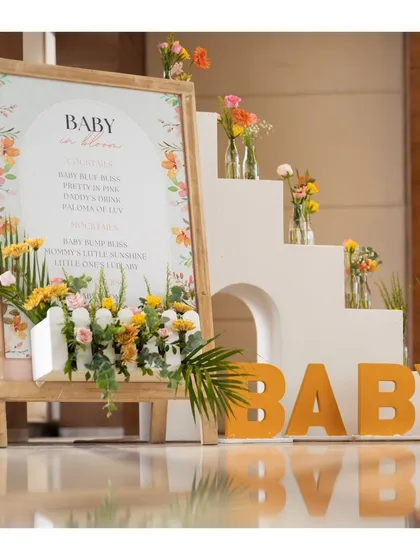 A clear, straight-on shot of the welcome decor, highlighting the modern typography on the sign and the artful arrangement of flowers in and around the display.