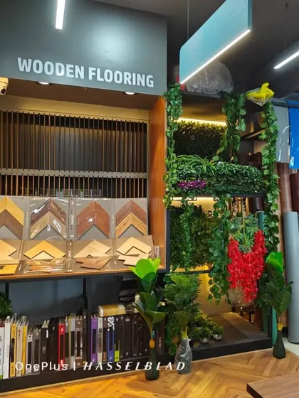 A glimpse into my experience store where you can see and feel the quality of my products. I have a wide range of wooden flooring samples, artificial grass types, and carpet textures on display. I always say, 'Banni, nodi, anandisi' (Come, see, enjoy).