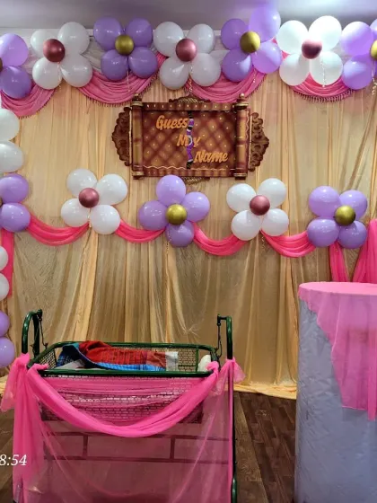The full stage for the balloon-themed naming ceremony, showing the complete arch and the placement of the cradle.