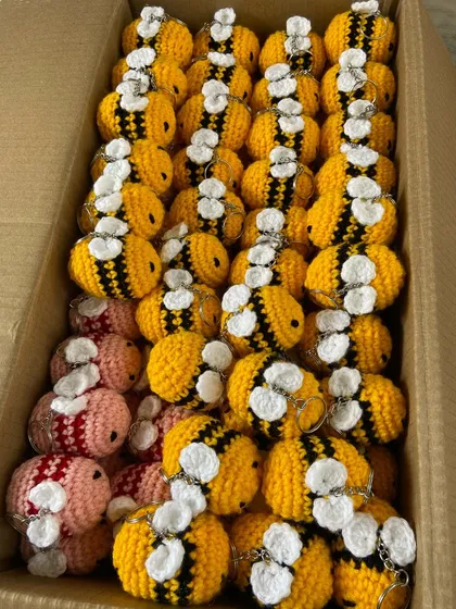A box full of happy bee keychains. I offer them in classic yellow and custom pink for clients looking for unique color variations.