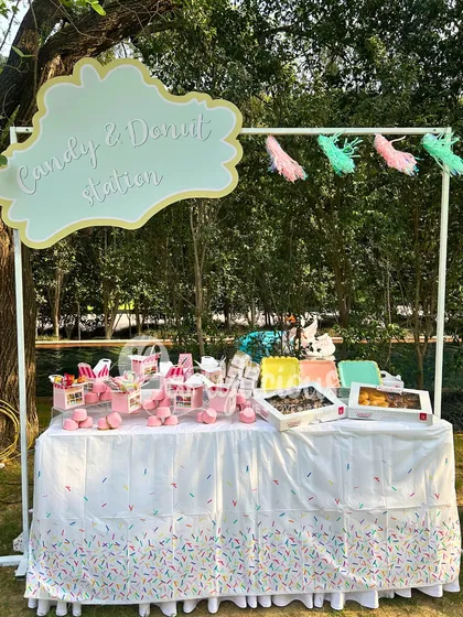 A candy and donut station is a must-have for any sweet-themed party. This one is perfectly styled with a custom sign and sprinkle-themed tablecloth.