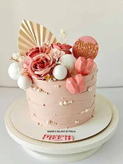 A sweet surprise from a husband to his wife. This pastel pink cake is adorned with soft florals, geometric chocolate hearts, and pearls for an elegant touch.
