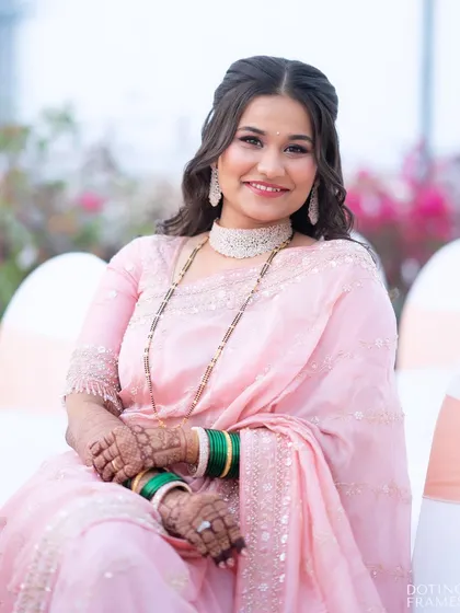 A beautiful seated portrait from her reception, showing the complete look with her elegant pink saree and diamond jewelry.