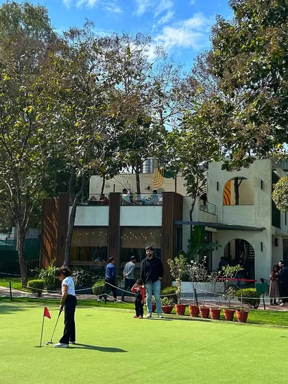 A young golfer practices her putting in front of the cafe, a perfect family-friendly activity.
