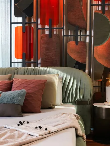 A close-up of the master bedroom at Matoshri Residence, showcasing our attention to detail. The design features a sage-green upholstered bed, a custom sculptural headboard with leather and veneer panels, and brass accents, creating a sanctuary of comfort and character.