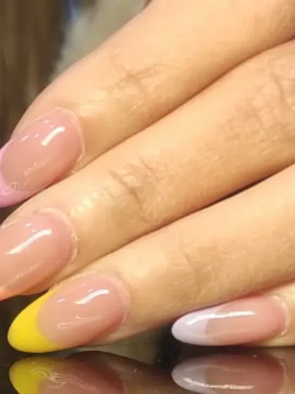A soft and pretty pastel French manicure, with each nail featuring a different colored tip in shades of pink, yellow, purple, and blue.