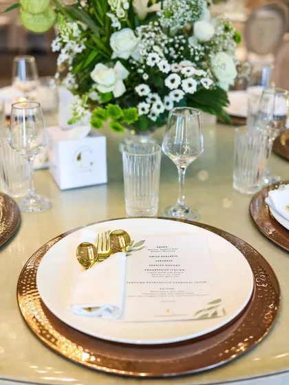 A beautifully coordinated place setting featuring hammered copper charger plates and a custom-printed menu. These details demonstrate our commitment to creating a cohesive and branded dining experience for your event.