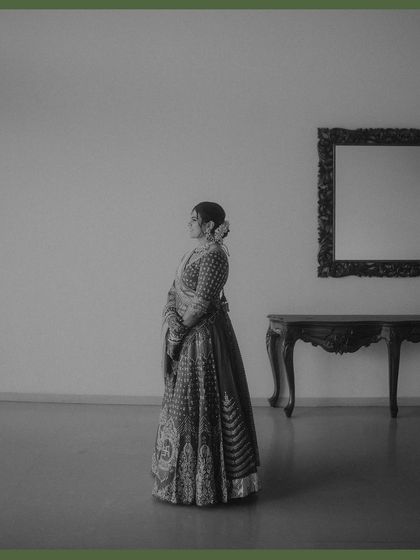 A minimalist black and white portrait of the bride standing in a spacious room. The simplicity of the frame holds a powerful sense of anticipation and elegance, proving that less is often more.