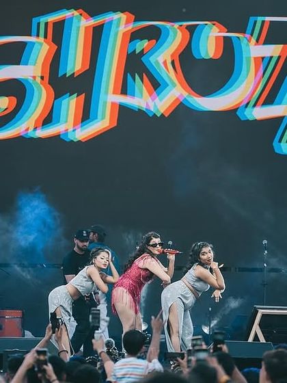 The view from the crowd, capturing the artist and dancers owning the stage under a massive, colorful logo. We design our choreography for maximum visual impact from every angle.