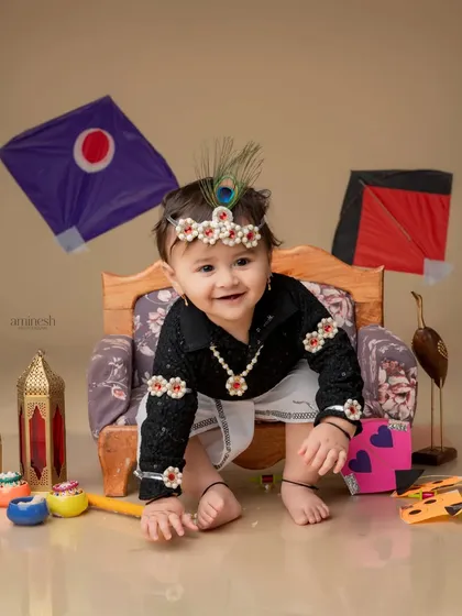 A sweet and playful pose from a baby girl during her Makar Sankranti shoot. The floral and peacock feather headband adds a unique and adorable touch to her outfit.