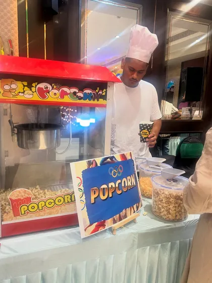 Our staff, dressed in a professional chef's uniform, serves fresh popcorn to guests at a birthday party.