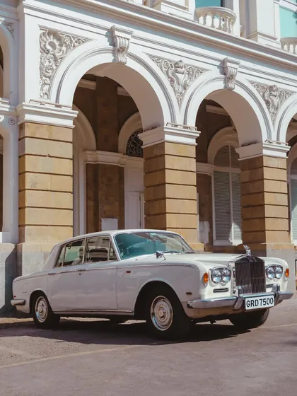 Nothing is more stunning than a classic car. This pristine white Rolls-Royce, parked in front of a stately building, is the definition of timeless elegance.