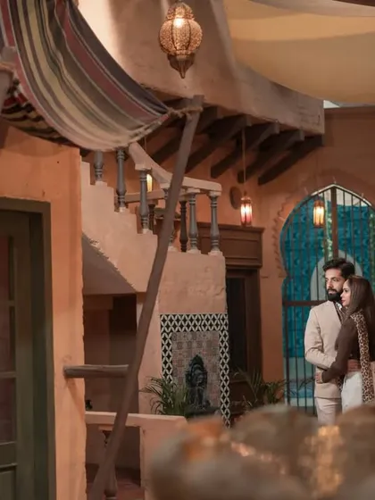 A wider view of the souk-themed set, showing the couple framed by the architecture and warm lighting, creating a cinematic and story-driven image.