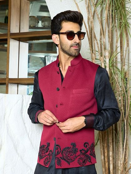 A sleek black kurta paired with a tailored maroon waistcoat. The jacket features delicate black embroidery along the hem, adding a touch of refined luxury.