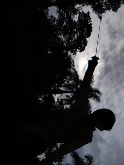 A fencer raises their foil in a victory salute. This pose, silhouetted against the clouds, symbolizes the aspiration and achievement we encourage in our students.