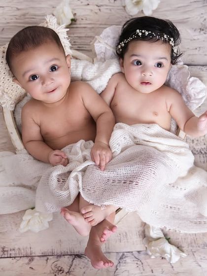 Adorable awake twins looking right at the camera! This portrait captures their budding personalities and the special bond they already share.