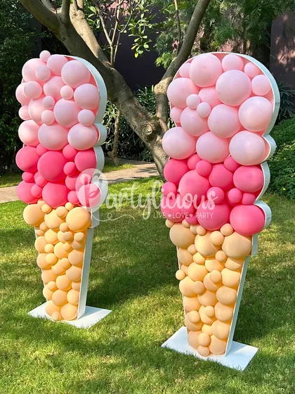 Two scoops are better than one! These matching giant ice cream cone props, made from pink and yellow balloons, create a symmetrical and impactful entrance or photo backdrop.