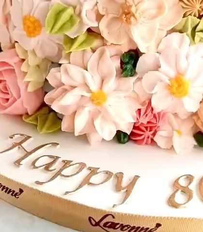 A detailed shot of the hand-piped buttercream flowers on the 80th birthday cake. Each flower is individually piped to create this lush, garden-like effect.