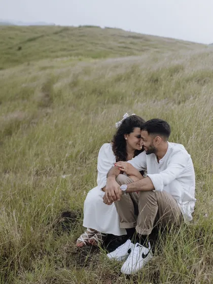 A sweet and intimate moment of the couple sitting together in a grassy field, lost in their own world.