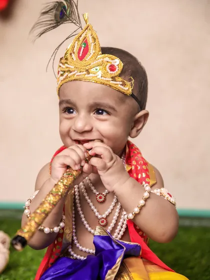 The pure joy of a child's smile is priceless. This little Krishna is captured in a moment of happiness, holding his flute, creating a heartwarming and candid portrait.