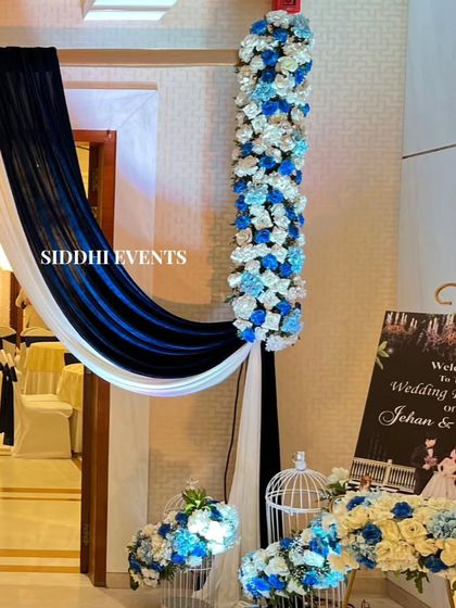A welcome sign for the wedding reception is beautifully integrated into the blue and white floral entrance decor, complete with decorative birdcages.