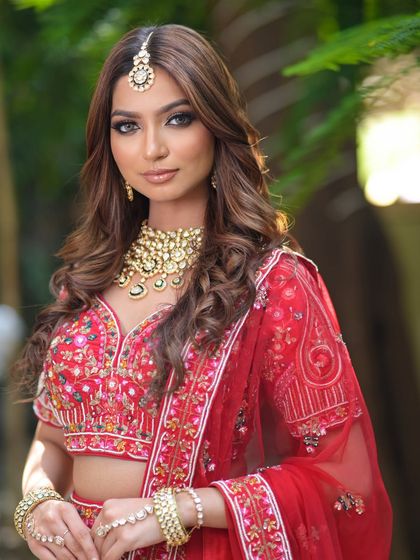 A beautiful shot capturing the elegance of a bride in a red lehenga. The matching jewellery set enhances the traditional look, all available for rent.
