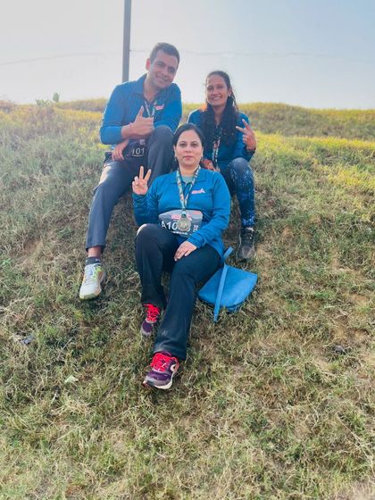 Runners taking a break and enjoying the moment on a grassy hill during the Aravali Run. It's about the journey, not just the race.