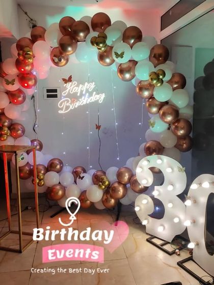A beautiful 30th birthday setup with a white and rose gold balloon ring, accented with butterfly details and a lit-up marquee number.