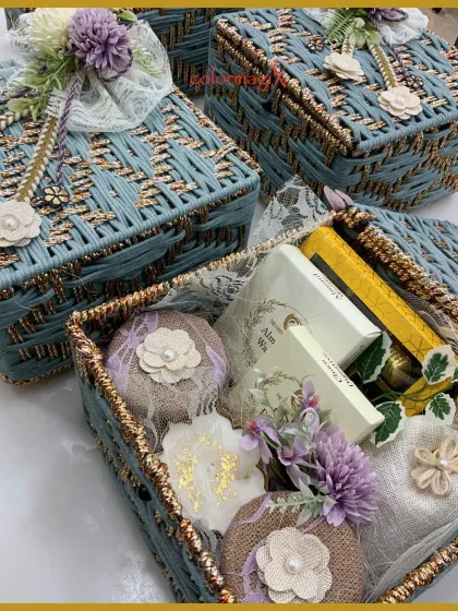 A close-up of our blue and gold woven basket, filled with beautifully packaged goodies and adorned with lace and floral details. It's a gift crafted with care.