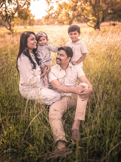 Togetherness is everything. This family finds a cozy spot in a sunlit field, creating a warm and rustic outdoor portrait that feels completely natural.