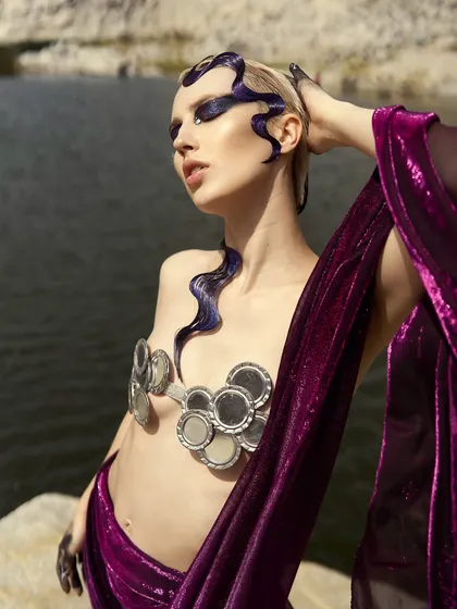 A powerful pose from the 'Siren' shoot, highlighting the dramatic makeup and the reflective quality of the mirror costume pieces.