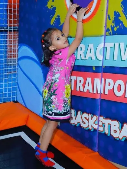 Our interactive trampoline area combines jumping with fun wall games. Here, a young guest reaches up to hit a target, adding a goal-oriented twist to the classic trampoline experience.