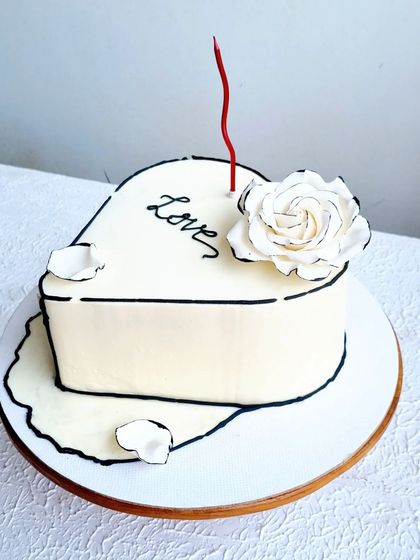 A heart-shaped cake with a 2D comic book effect. The design features a single, hand-made sugar rose with black-edged petals.