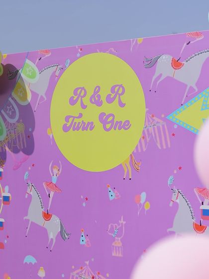 A close-up of the custom-printed backdrop for the twins' "R & R Turn One" carnival party. The whimsical circus-themed pattern adds a unique and personalized touch to the event's decor.