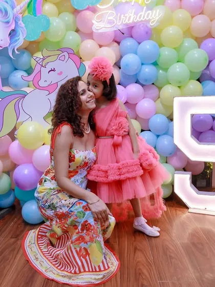 A sweet moment between mother and daughter in front of the magical unicorn birthday backdrop, complete with a light-up number '5'.