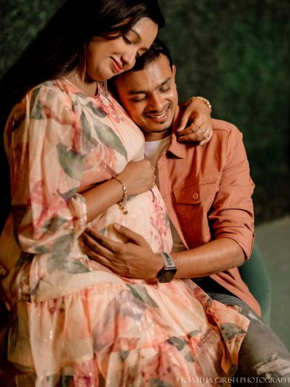 A joyful close-up of an expecting father embracing his partner from behind. His happy smile and her serene expression perfectly capture the excitement of this time.