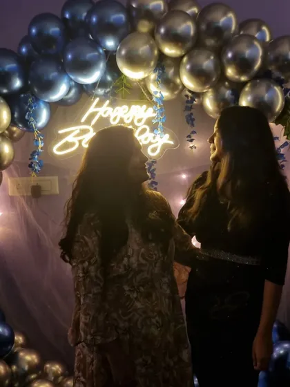Two friends posing in front of the blue and silver birthday balloon arch. It's all about making memories with your favorite people.