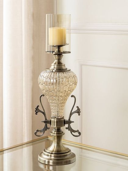 This candle stand features a beautiful mix of textured glass and antiqued metal with ornate scrollwork. It has a stately presence, perfect for adding a touch of vintage glamour to a side table or mantelpiece.