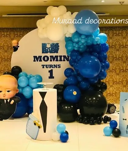 Here's another fun Boss Baby setup for a first birthday. This one features a large circular backdrop with custom text, character props, and a dynamic balloon arrangement in blue, black, and white.